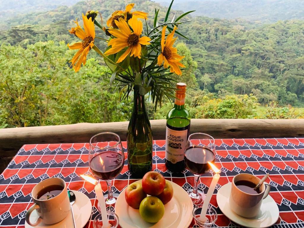 a table with a bottle of wine and a vase of flowers at Bwindi Neckview Lodge in Buhoma