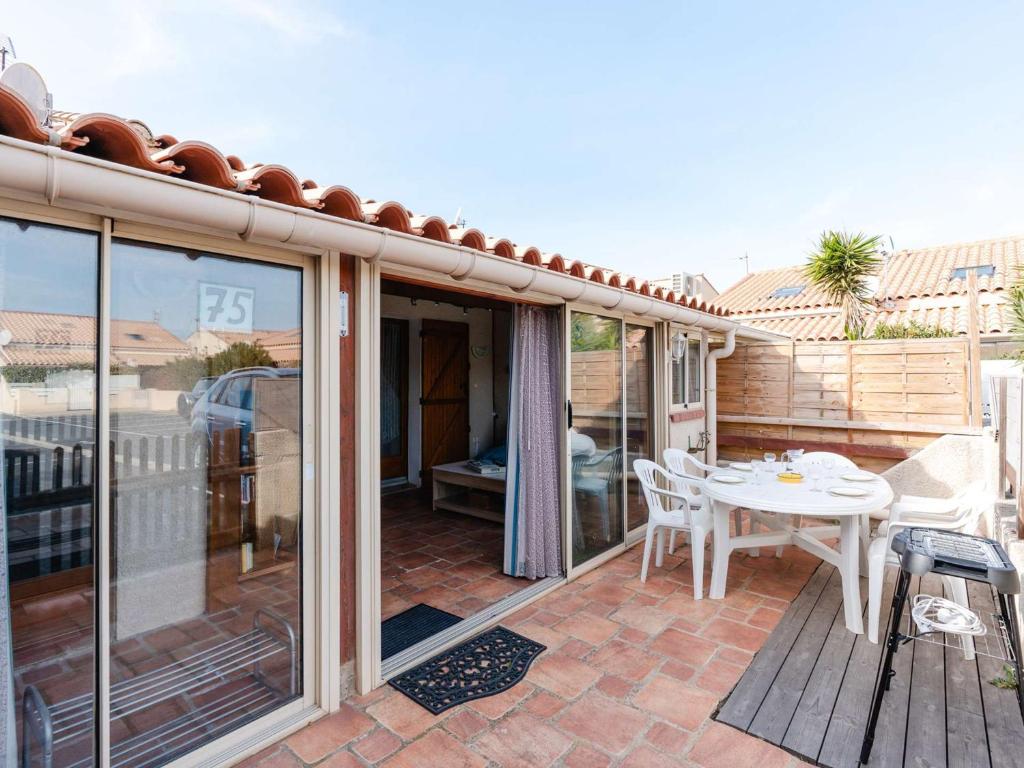 un patio avec une table et des chaises sur une terrasse dans l'établissement Pavillon Climatisé T2 Mezzanine à 150m de la Plage - 5 Pers, Parking, Animaux Acceptés - FR-1-409-250, à Gruissan