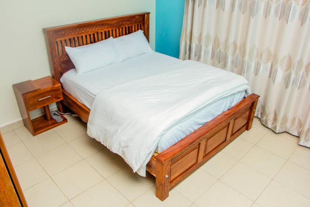 een slaapkamer met een bed met een houten frame bij Spacious- Brb Homes Bukoto in Kampala