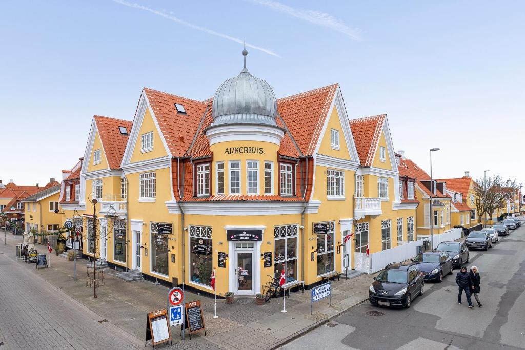 a large yellow building on a street with parked cars at Ankerhus Skagen in Skagen