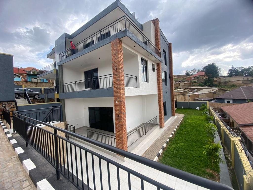 a house with a balcony with a person sitting on the balcony at Muyovu Apartment in Kigali