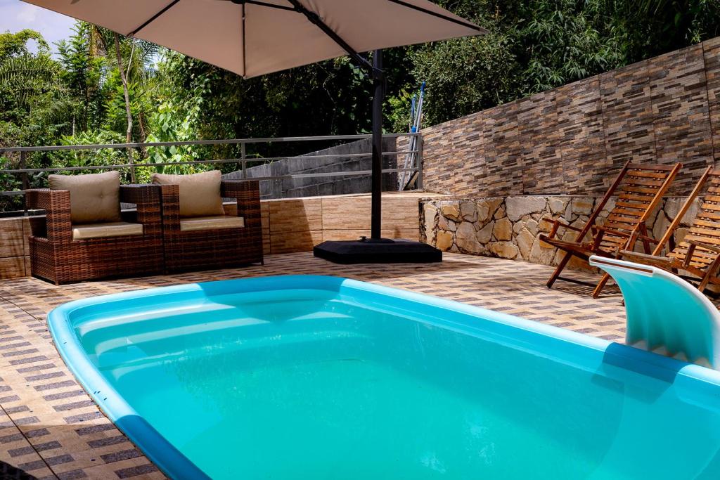 uma piscina com um guarda-sol e duas cadeiras e um pátio em Chacara em otima localizacao em Arthur Nogueira SP em Artur Nogueira