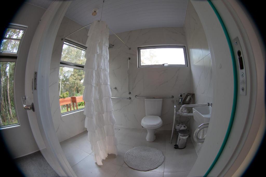 La salle de bains blanche est pourvue de toilettes et d'une fenêtre. dans l'établissement Casa Ócio By Canela do Mato, à Palomas