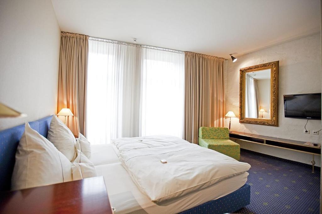 Una habitación de hotel con una cama grande y un espejo. en Hotel Lehmeier, en Neumarkt in der Oberpfalz