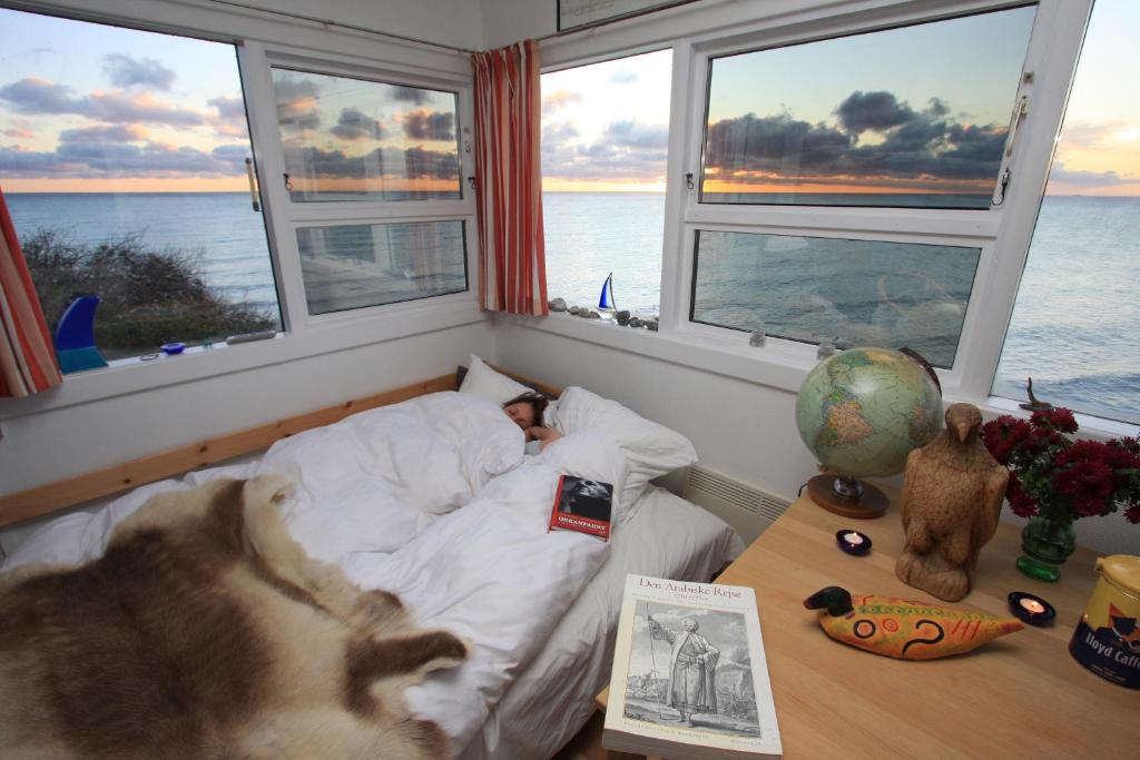 a child sleeping in a bed in a room with windows at The Lighthouse Cabin in Borre