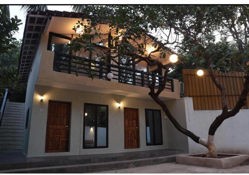 a house with a balcony and a tree in front of it at Glass Luxe Villa in Mumbai