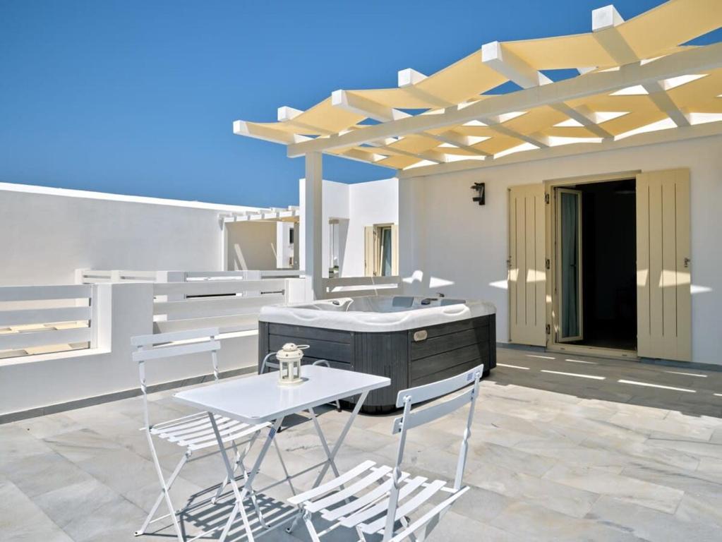 a patio with a tub and two chairs and a table at Villa Maria - Naoussa Fishes Blue & Grey Suite in Naousa