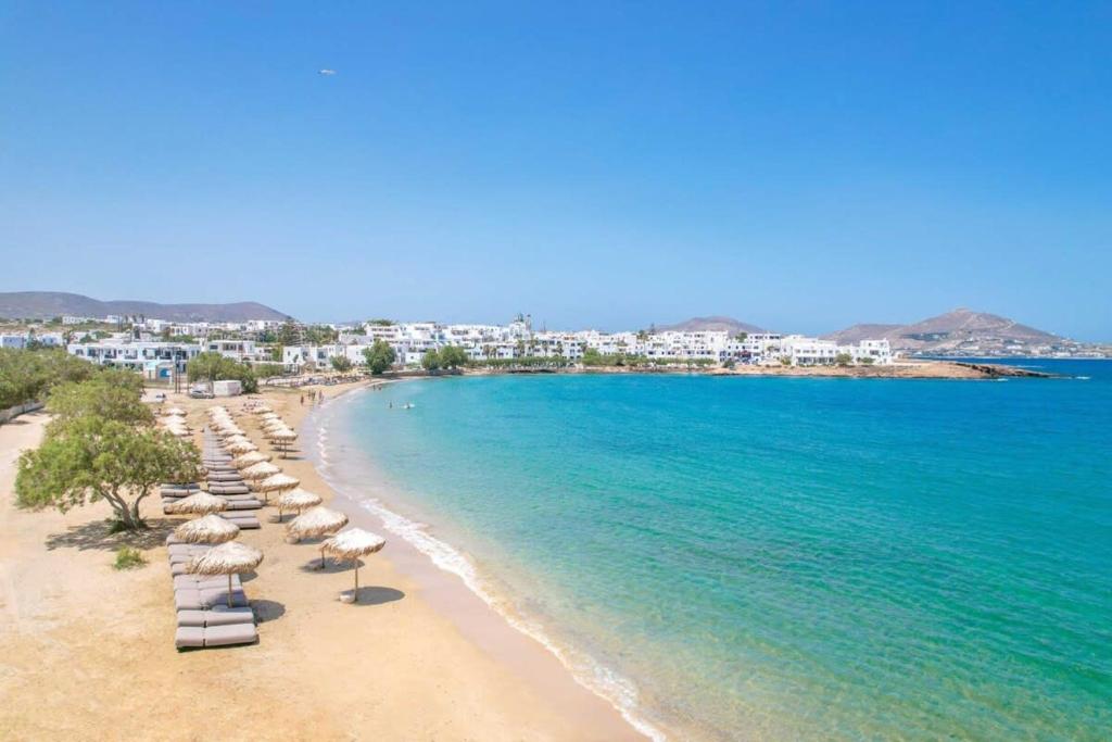 een strand met stoelen en parasols en de oceaan bij Villa Maria - Naoussa Squares Blue & Gold Suite in Naousa
