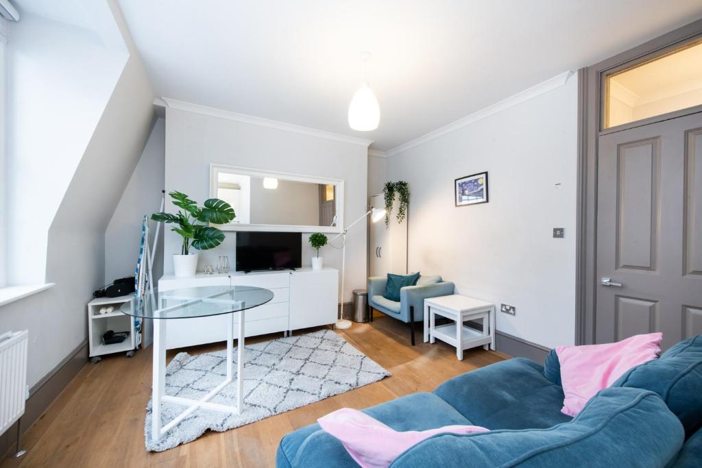 a living room with a blue couch and a glass table at 2Bed Cosy Flat in Vibrant Fitzrovia in London