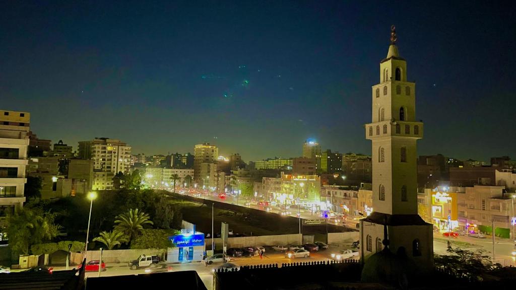 uma alta torre de relógio branco em uma cidade à noite em fantazia pyramids inn no Cairo