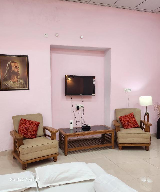 a living room with two chairs and a tv on the wall at NICTBS in Prayagraj