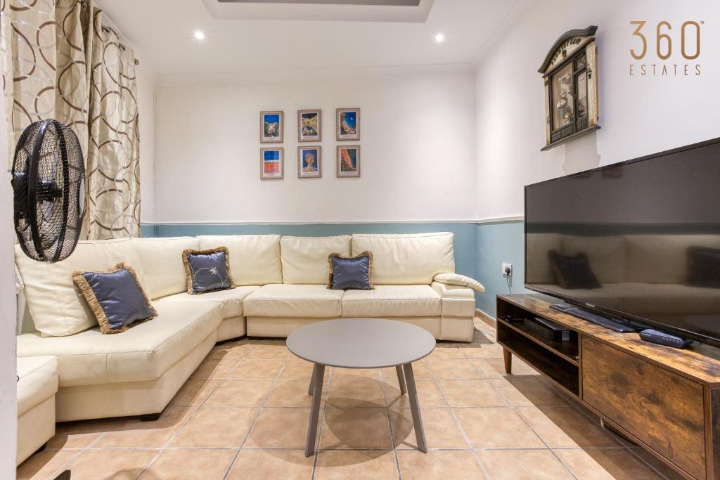 ein Wohnzimmer mit einem Sofa und einem Flachbild-TV in der Unterkunft Charming & Cosy 2BR home with WIFI in Birgu by 360 Estates in Vittoriosa