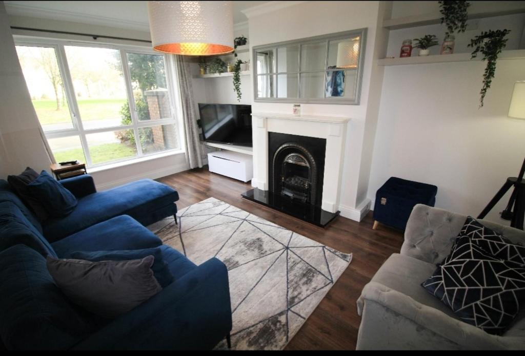 a living room with a blue couch and a fireplace at Stylish Spacious 4 Bedroom House in Galway