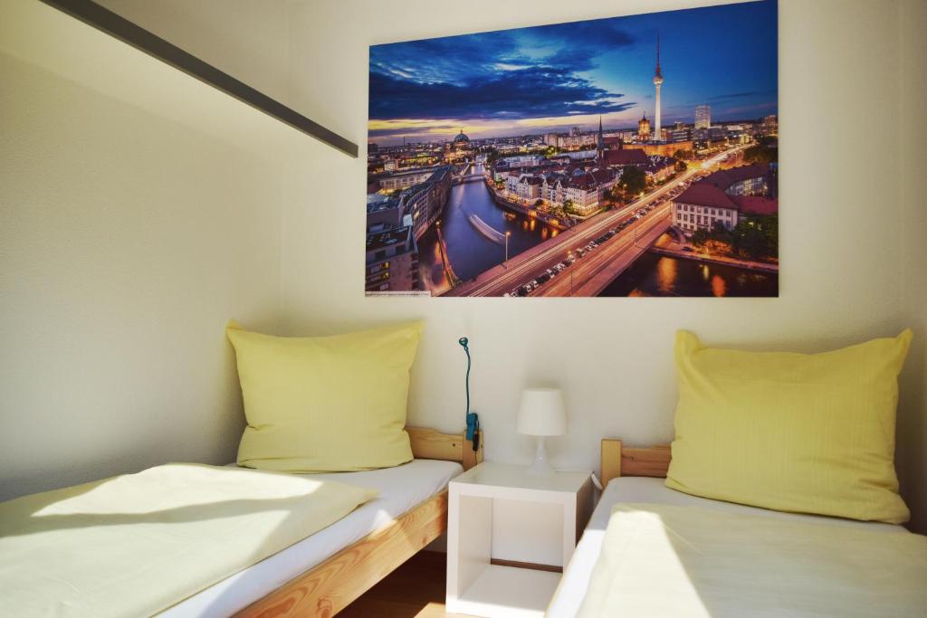 - 2 lits dans une chambre avec une photo sur le mur dans l'établissement CLUB Lodges Berlin Mitte, à Berlin