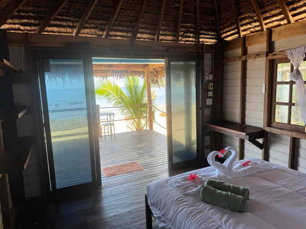 a bedroom with a bed with a view of the beach at Sunset Beach Bungalow Koh Pu in Ko Jum