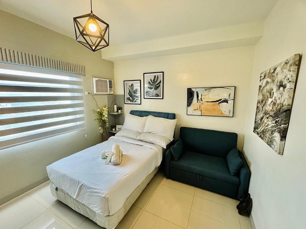 a bedroom with a bed and a green chair at Studio Casa Mira Tower 2 in Cebu City