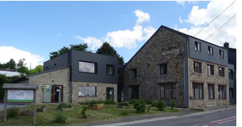 un ancien bâtiment en pierre avec un toit noir dans l'établissement Le Fagotin - Youth hostel, à Stoumont