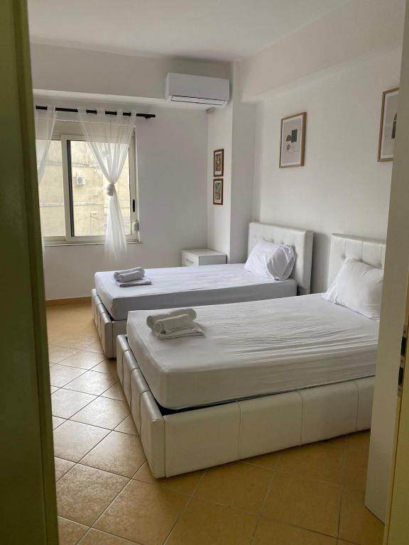 two beds in a white room with a window at Nicole Apartments Rental in Durrës