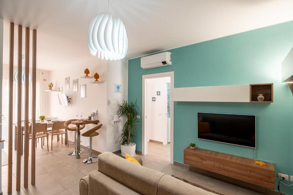 uma sala de estar com um sofá e uma televisão na parede em KELIFOS Comfort Apartment em SantʼAgata di Militello