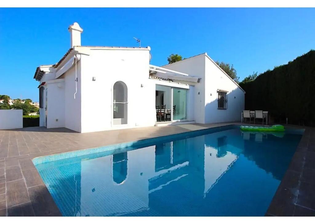 una casa blanca con piscina frente a ella en Verano, en Benissa