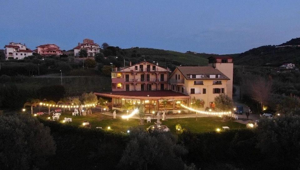 a large building with lights in a yard at night at Agriturismo Fonte Madonna in Mirto