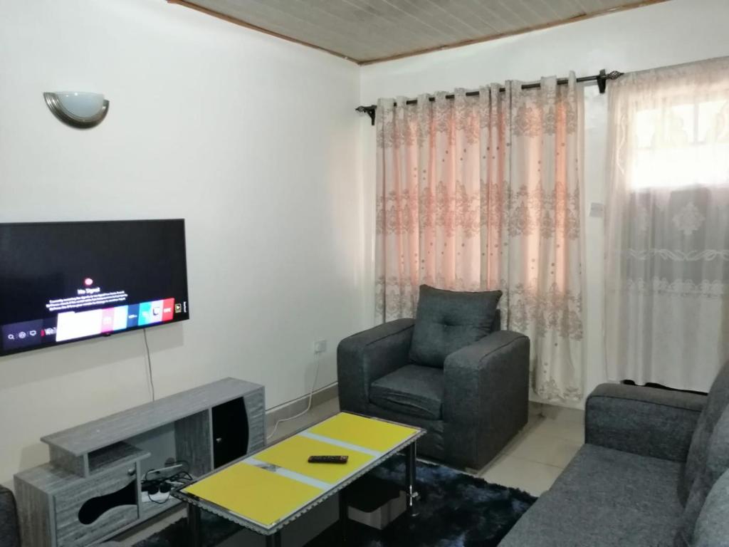 sala de estar con sofá, silla y TV en Klimax Place, en Kiambu