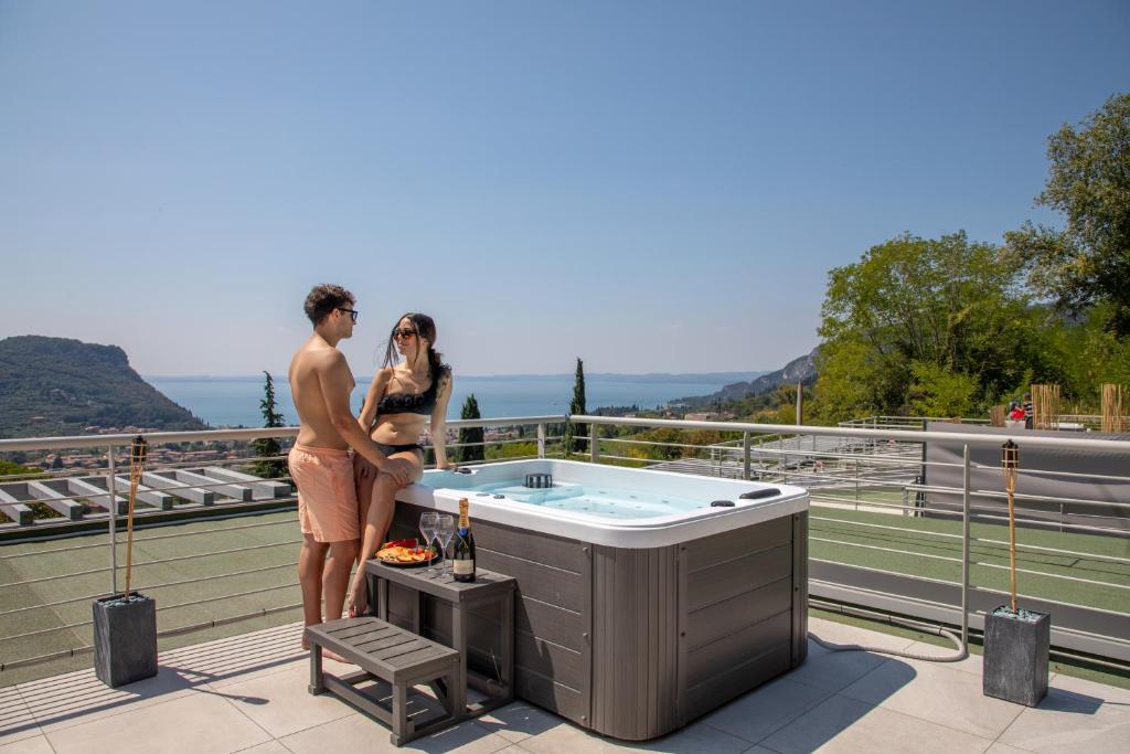 un hombre y una mujer de pie junto a una bañera de hidromasaje en el techo en Sunset Lodge en Garda