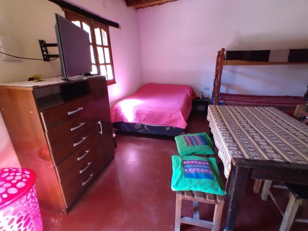 a bedroom with a bed and a dresser with a television at CABAÑAS LA LUCRECIA mono in Humahuaca