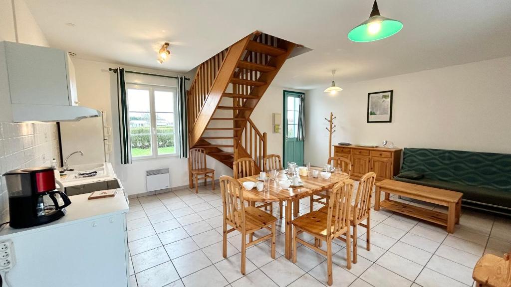 a kitchen and a dining room with a table and chairs at Pommeraie et Eglantines in Quend