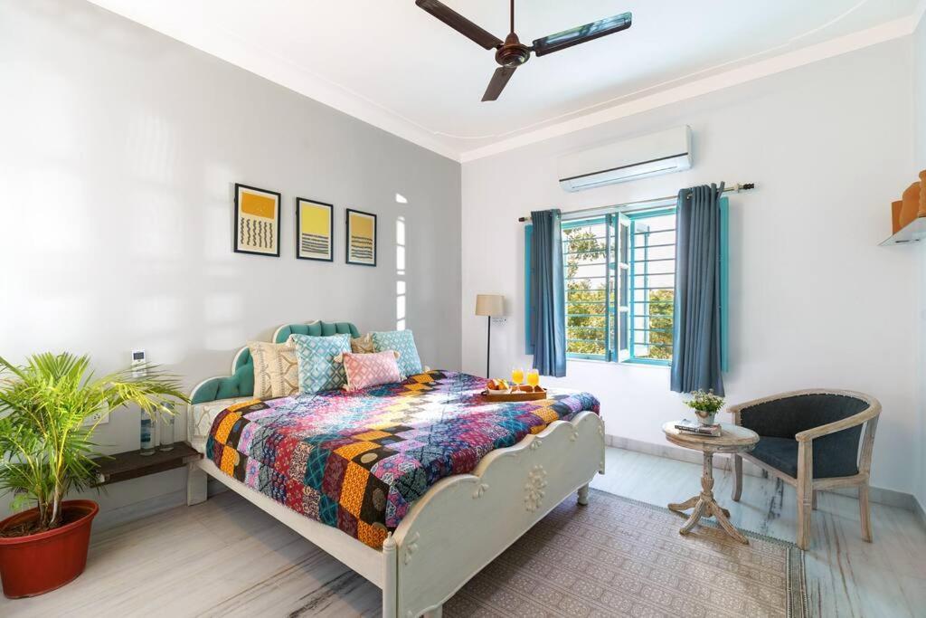 ein Schlafzimmer mit einem Bett, einem Stuhl und einem Fenster in der Unterkunft Thaharo 2 BHK Luxurious Villa in Udaipur in Thūr