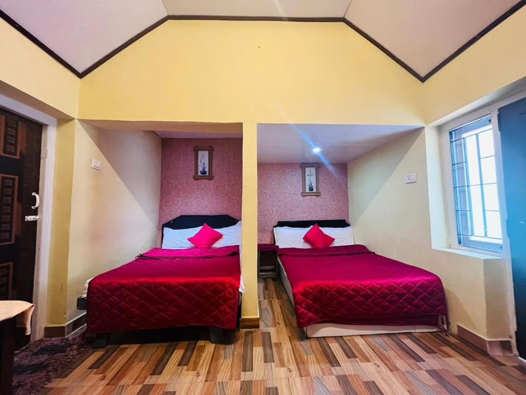 two beds in a room with red sheets at Brickhouse in Kodaikānāl