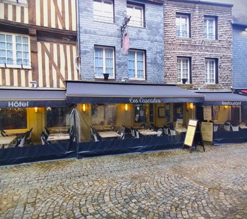 um edifício com um restaurante com mesas em frente em Les Cascades - Hôtel de Charme em Honfleur