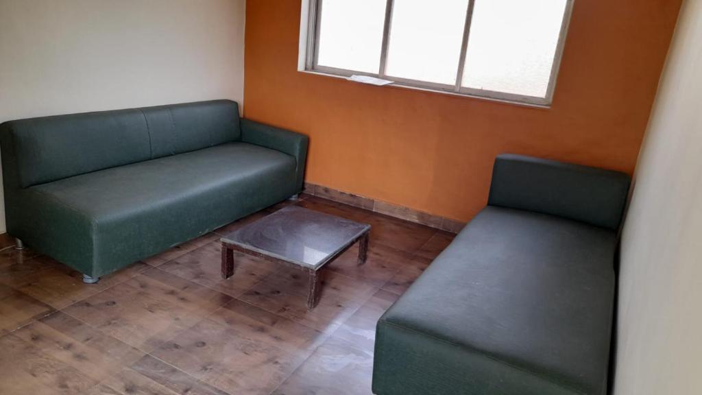twee groene stoelen en een tafel in een kamer bij Butaliaji's House in Khopoli