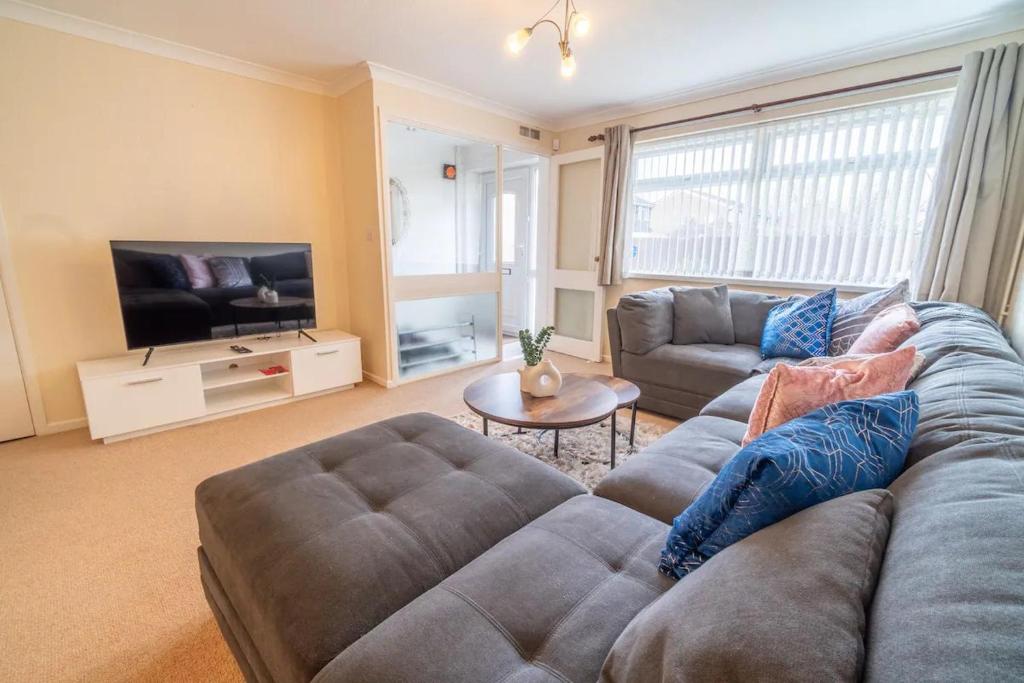 ein Wohnzimmer mit einem Sofa und einem TV in der Unterkunft Pass the Keys Stylish 3 bedroom home with free parking in Nottingham