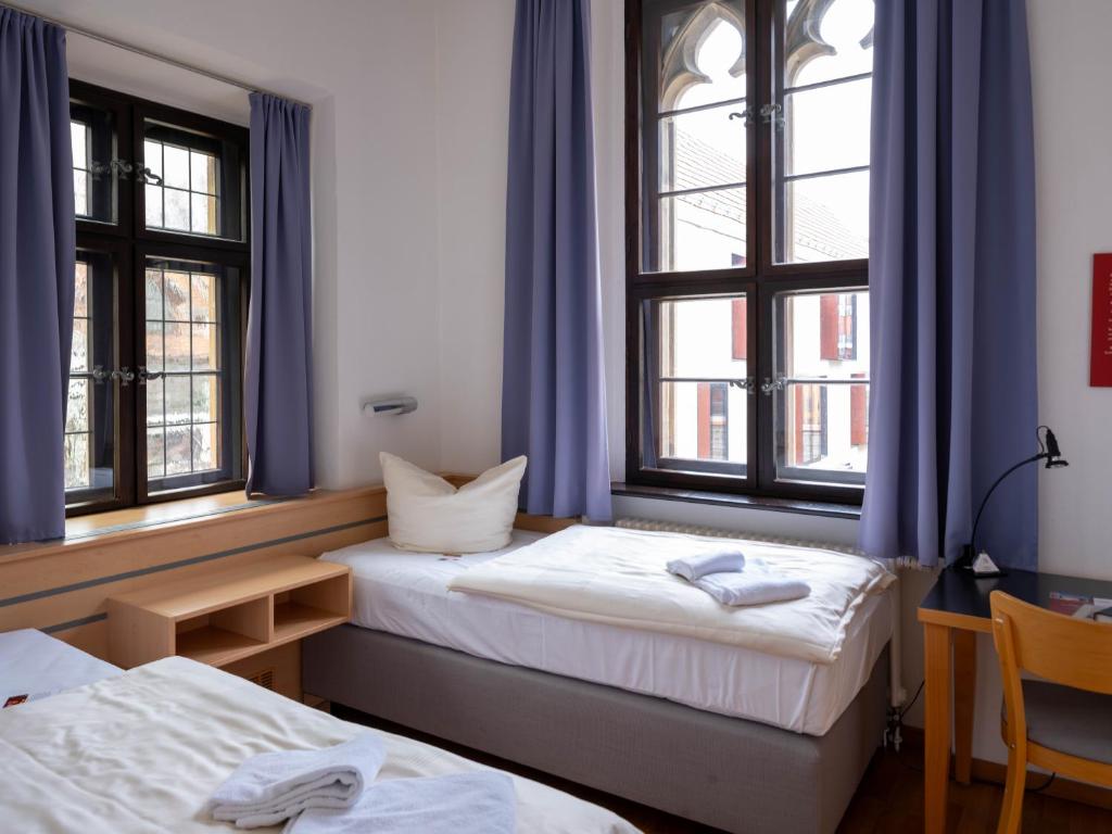 Postel nebo postele na pokoji v ubytování Ev. Augustinerkloster zu Erfurt