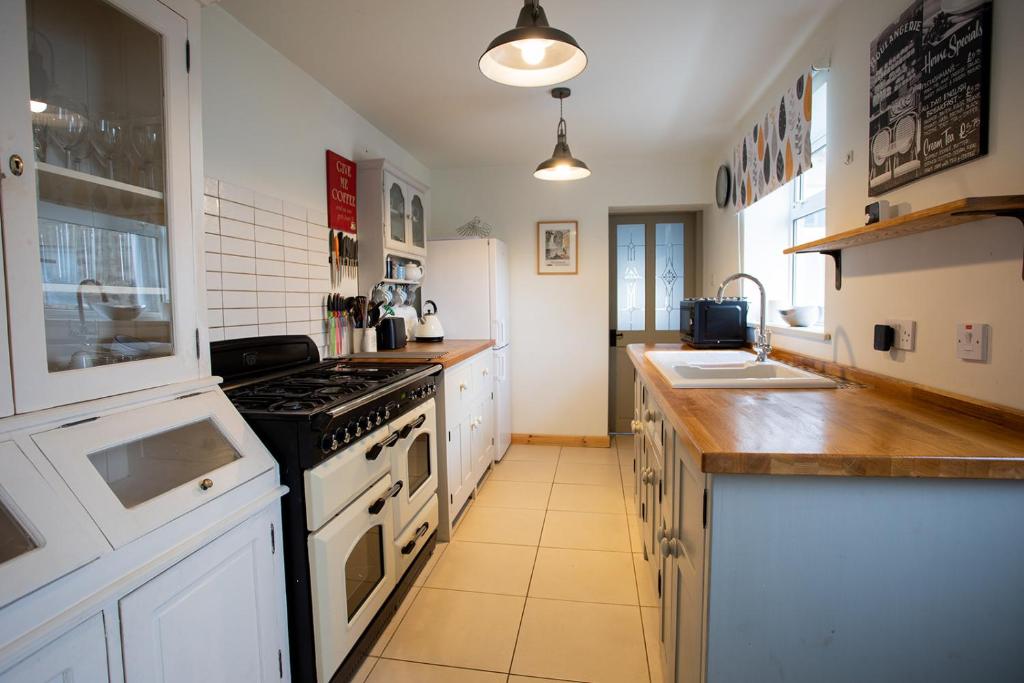 een keuken met witte kasten en een fornuis met oven bij Tilly Cottage, DurhamDales in Bishop Auckland