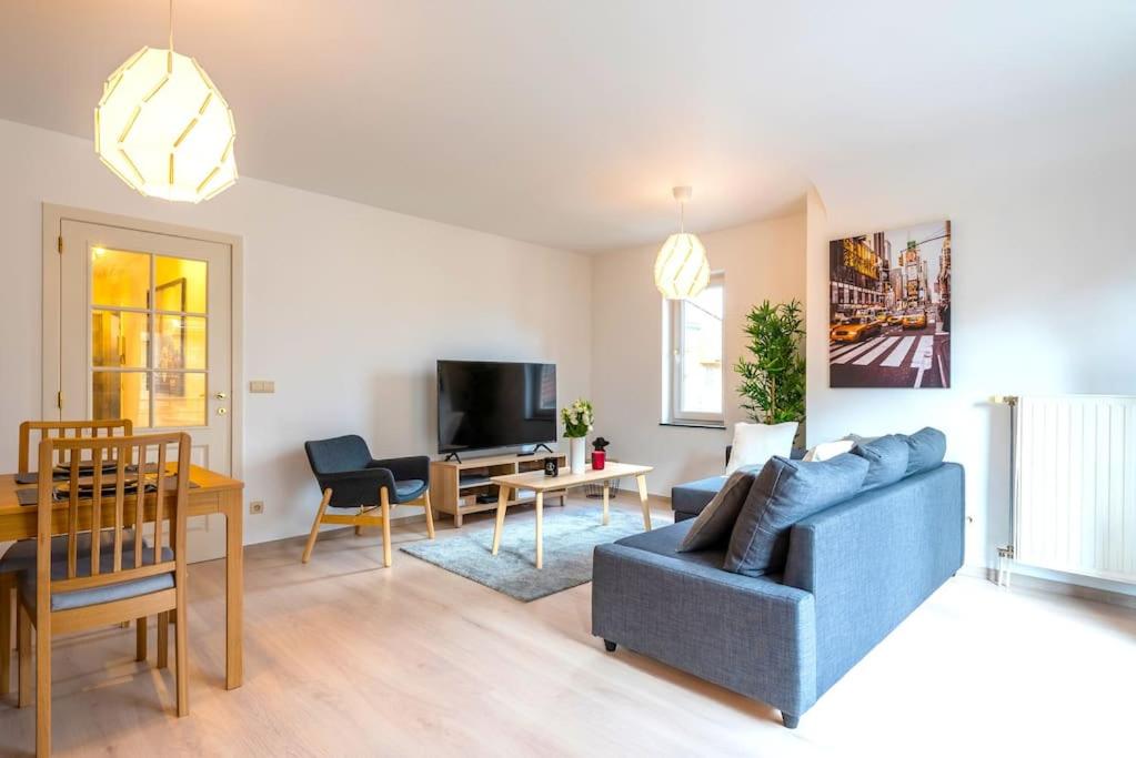 ein Wohnzimmer mit einem blauen Sofa und einem Tisch in der Unterkunft Jette Expo Duplex Residence in Brüssel