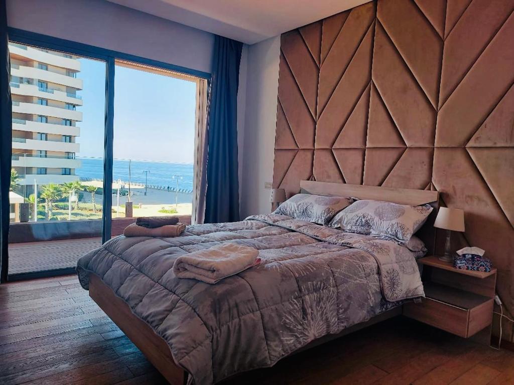 a bedroom with a large bed and a large window at Magnifique appartement pleine vue mer Marina Casablanca in Casablanca