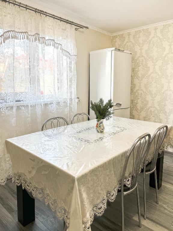 une table blanche avec des chaises et un réfrigérateur blanc dans l'établissement Софія, à Yasinya