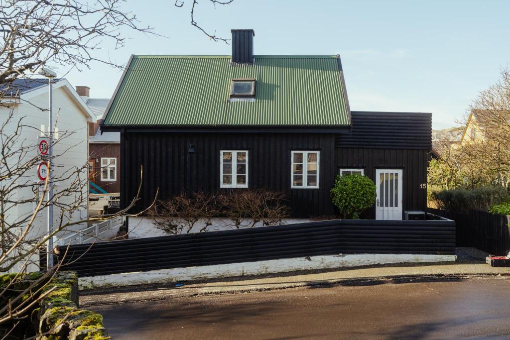 a black house with a green roof at Charming Retreat in the Heart of Tórshavn in Tórshavn