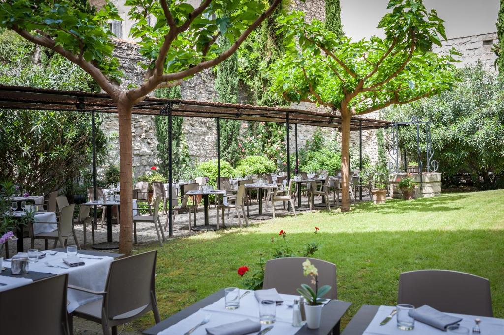 a patio area with tables, chairs and umbrellas at Hôtel Cloitre Saint Louis Avignon in Avignon