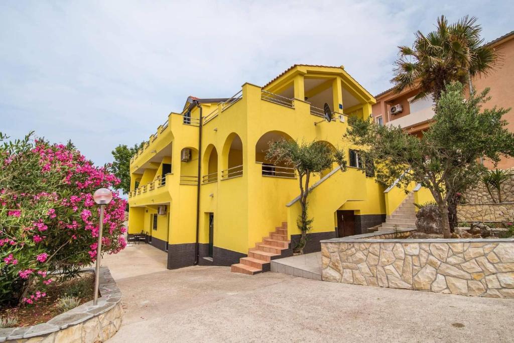 a yellow house with trees and pink flowers at Sunce in Vrbnik