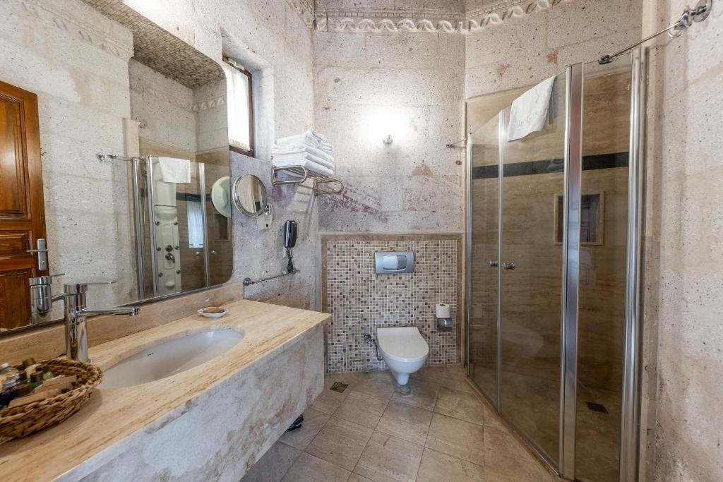 a bathroom with a sink and a shower and a toilet at Cappadocia Cave Suites Adult Only in Goreme