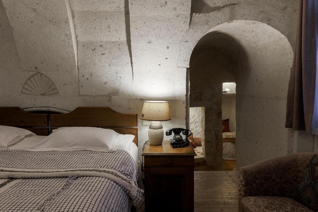 1 dormitorio con 1 cama y 1 lámpara en una mesa en Cappadocia Cave Suites, en Göreme