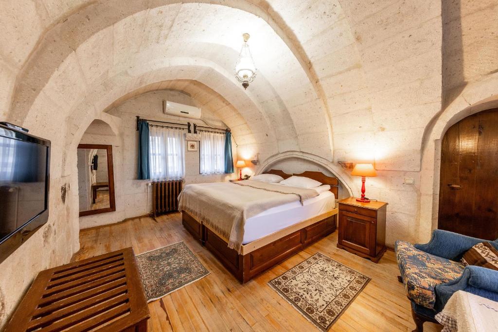a bedroom with a bed and a tv and a couch at Cappadocia Cave Suites Adult Only in Goreme