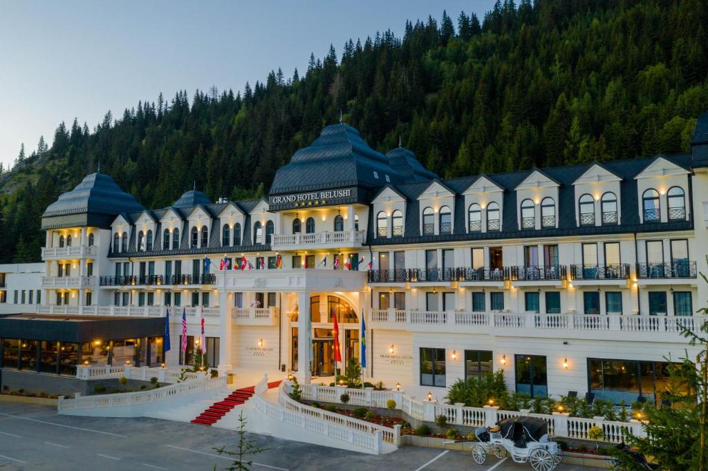 un gran edificio blanco con una montaña en el fondo en Grand Hotel Belushi, en Boge