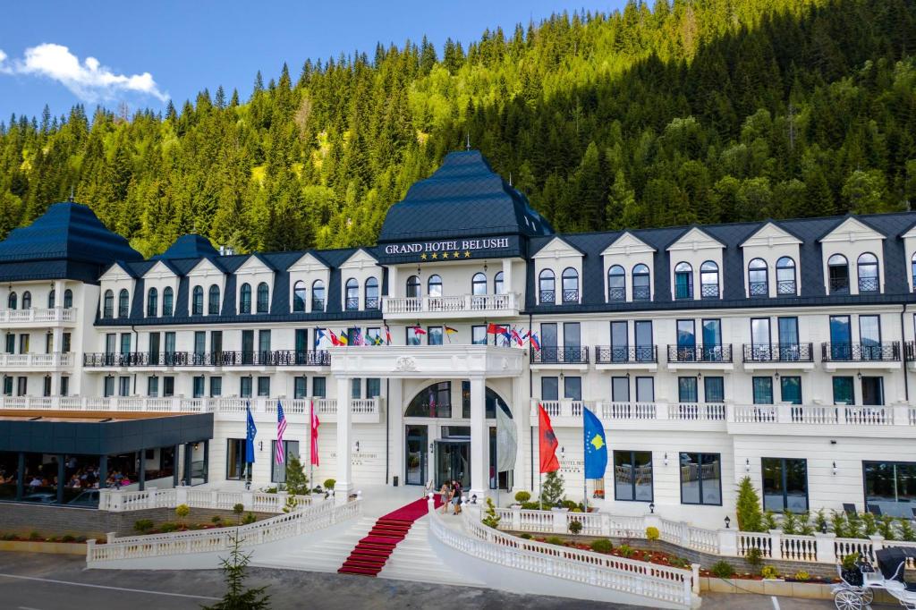 un gran edificio blanco con una montaña en el fondo en Grand Hotel Belushi, en Boge