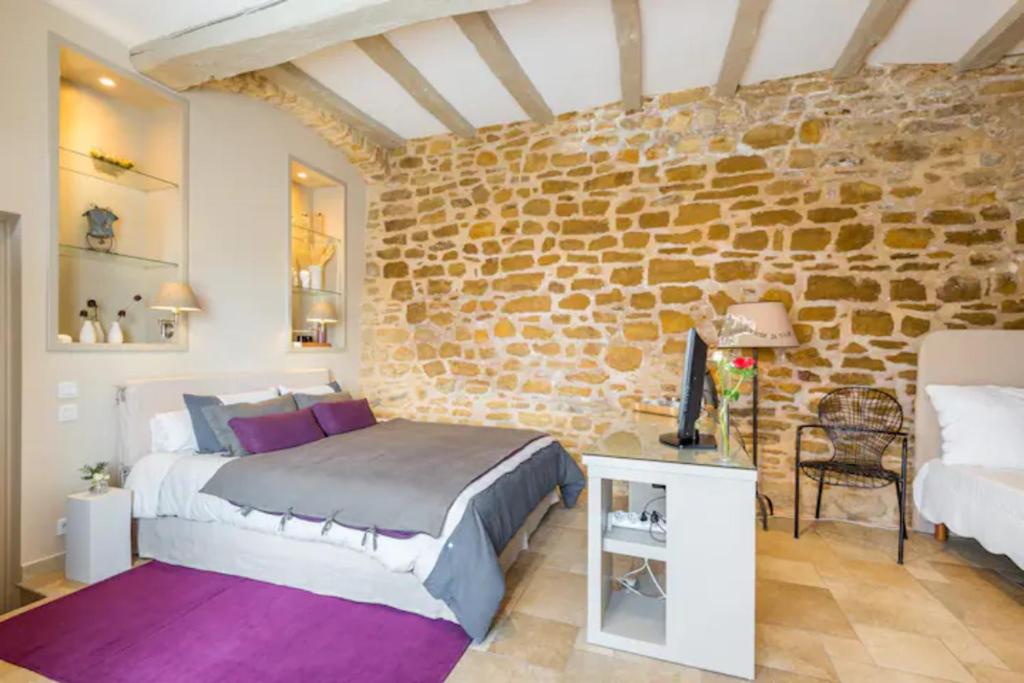 1 dormitorio con cama y pared de ladrillo en Les Terrasses Dorées - Chambres d'hôtes de charme & Jacuzzi, en Châtillon