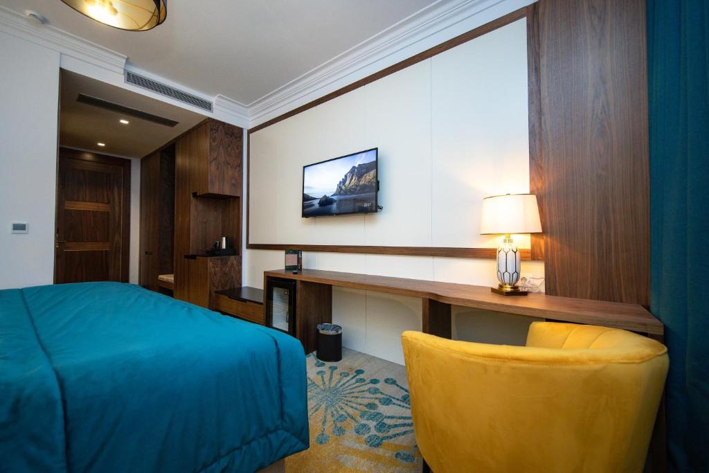 Dormitorio con escritorio, cama y silla amarilla en Grand Hotel Belushi, en Boge