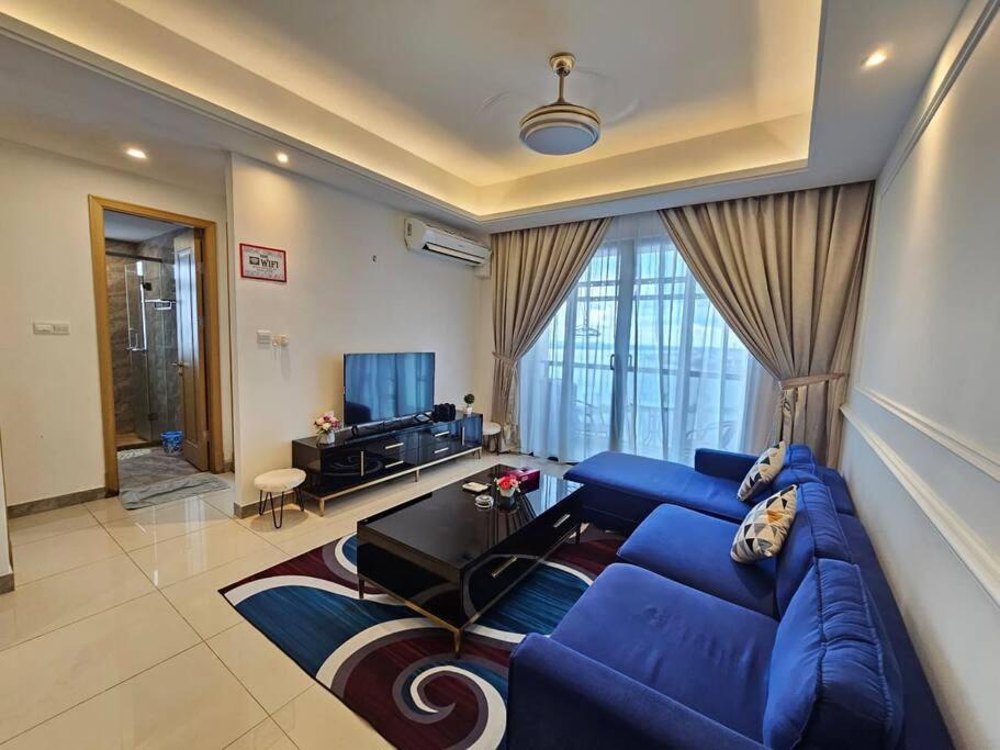 ein Wohnzimmer mit einem blauen Sofa und einem Tisch in der Unterkunft R&F Princess Cove & R&F Mall by QQ BnB in Johor Bahru